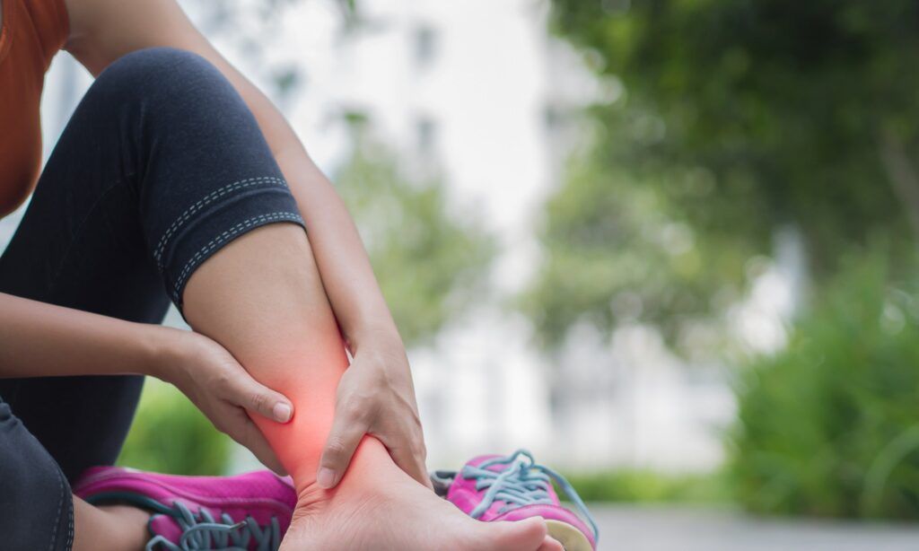 Woman outdoors holding painful shin area, indicating shin pain and chiropractic treatment in Sydney